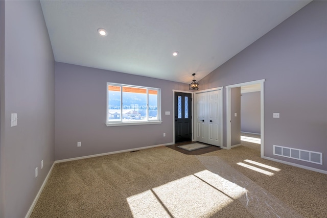 foyer featuring vaulted ceiling and carpet