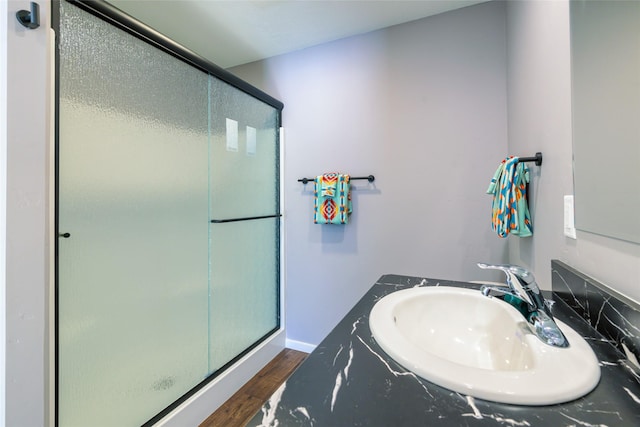 bathroom with hardwood / wood-style flooring, vanity, and walk in shower