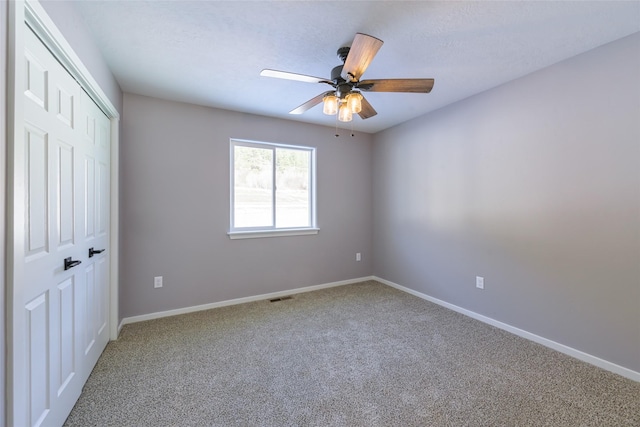 carpeted spare room featuring ceiling fan