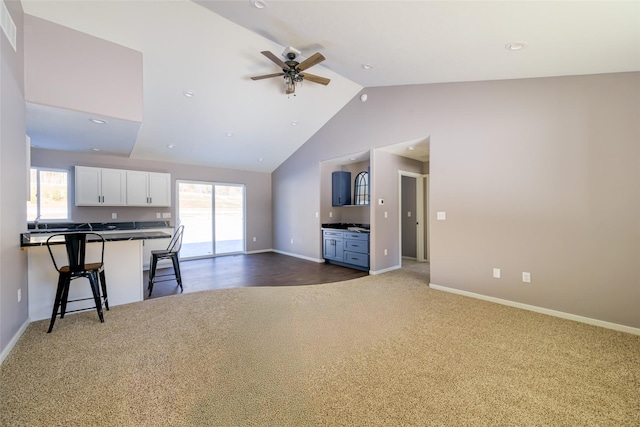 unfurnished living room with ceiling fan, lofted ceiling, and dark carpet