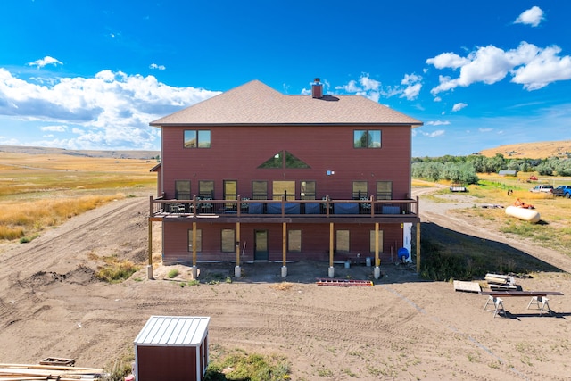 back of property featuring a deck with mountain view and a rural view