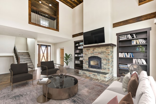 living room with dark hardwood / wood-style flooring, built in shelves, a fireplace, and a high ceiling