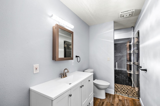 bathroom with vanity, toilet, hardwood / wood-style floors, and a shower