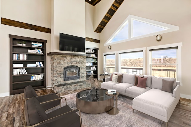 living room with a high ceiling, wood-type flooring, a fireplace, and built in shelves