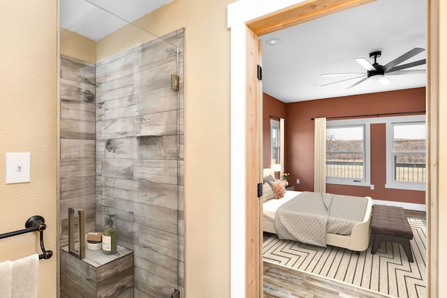 bathroom featuring hardwood / wood-style floors, a shower with shower door, and ceiling fan