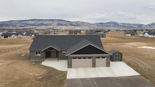 view of front of house with stone siding, fence, a mountain view, concrete driveway, and an attached garage