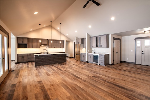 kitchen featuring beverage cooler, freestanding refrigerator, a sink, light countertops, and wall chimney range hood