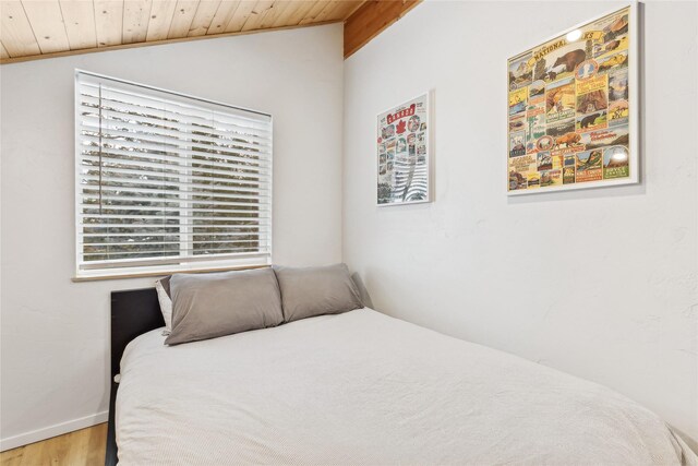 bedroom with vaulted ceiling, wooden ceiling, and light hardwood / wood-style floors