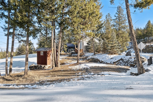 yard covered in snow featuring a shed and an outbuilding