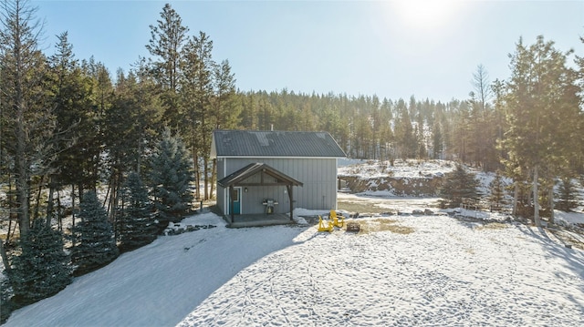 view of front of home with metal roof and a view of trees