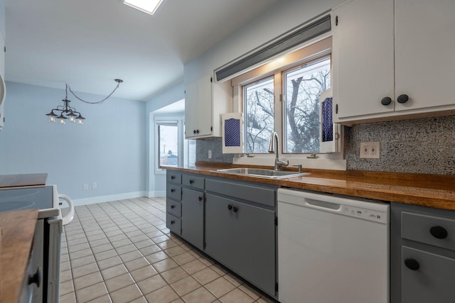 kitchen with sink, range, white dishwasher, white cabinets, and light tile patterned flooring