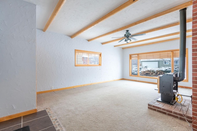 living room featuring ceiling fan, carpet floors, a textured ceiling, beamed ceiling, and a wood stove