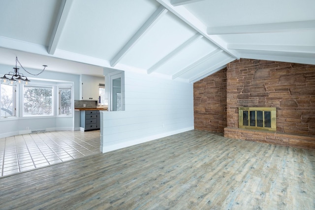 unfurnished living room with a stone fireplace, a chandelier, light hardwood / wood-style floors, and vaulted ceiling with beams