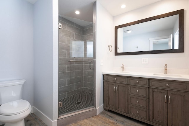 bathroom with wood-type flooring, toilet, a shower with shower door, and vanity