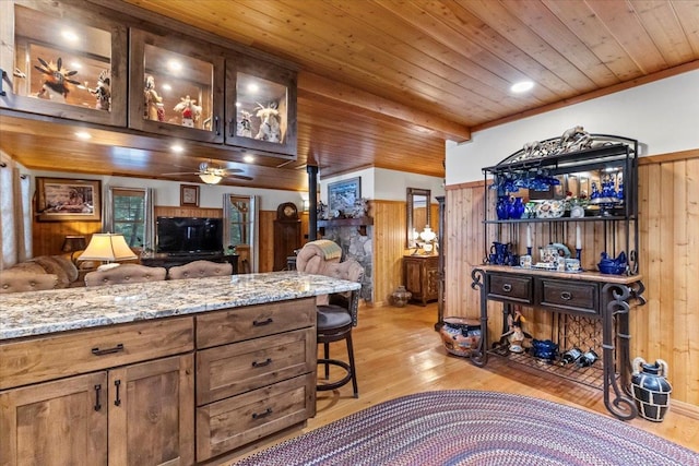 192 Crystal Lakes Dr, Eureka, MT 59917 - kitchen with wooden walls, light wood finished floors, light stone counters, wooden ceiling, and a breakfast bar area