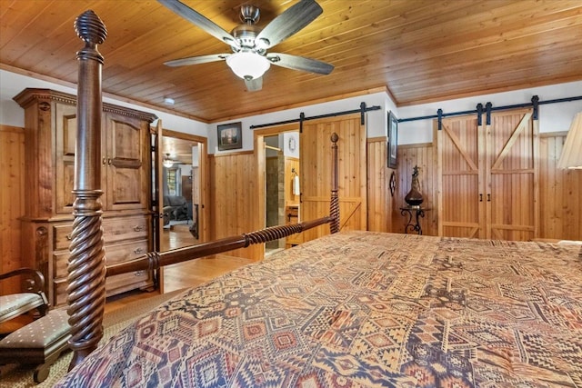 192 Crystal Lakes Dr, Eureka, MT 59917 - bedroom featuring wooden ceiling, a barn door, wood walls, wood finished floors, and wainscoting