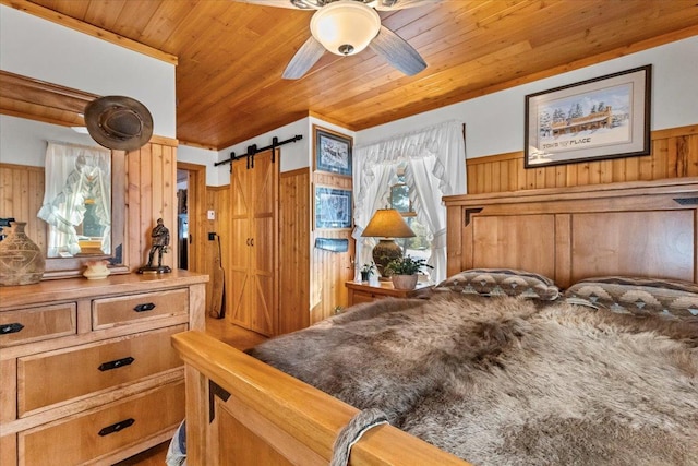 192 Crystal Lakes Dr, Eureka, MT 59917 - bedroom with wood walls, wooden ceiling, a barn door, and a wainscoted wall