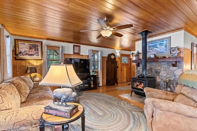 192 Crystal Lakes Dr, Eureka, MT 59917 - living room featuring a wood stove, wood ceiling, wood finished floors, a ceiling fan, and wood walls