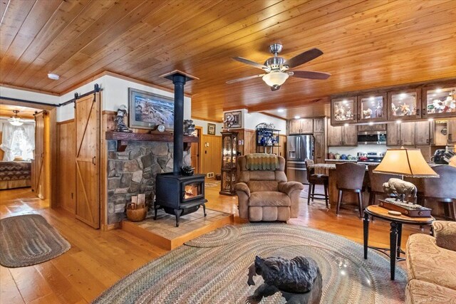 192 Crystal Lakes Dr, Eureka, MT 59917 - living area with wooden ceiling, a wood stove, light wood-type flooring, a ceiling fan, and a barn door