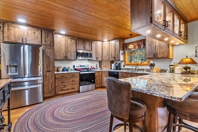 192 Crystal Lakes Dr, Eureka, MT 59917 - kitchen with stainless steel appliances, wood ceiling, a peninsula, a sink, and a kitchen bar