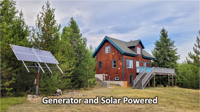 rear view of house with central air condition unit and solar panels