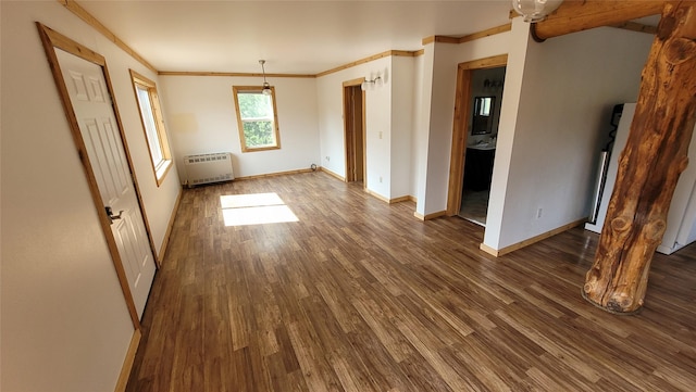 spare room with crown molding, dark wood-type flooring, and radiator heating unit