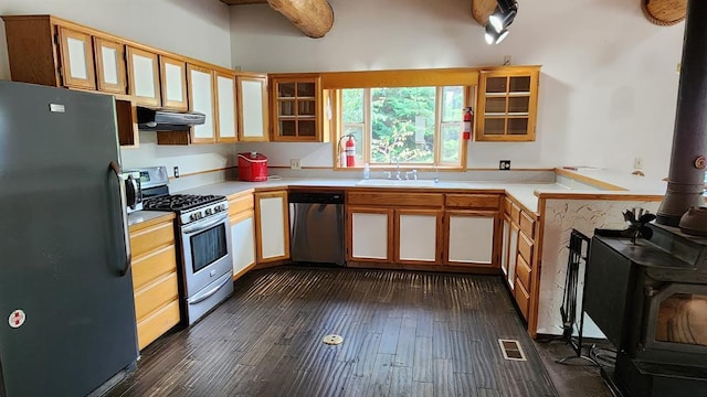 kitchen with appliances with stainless steel finishes, sink, a wood stove, kitchen peninsula, and dark wood-type flooring