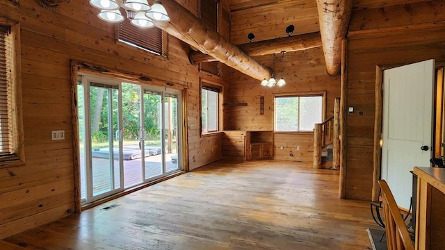 interior space with an inviting chandelier, wooden walls, beamed ceiling, and wood-type flooring