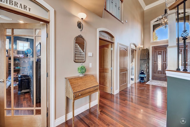 foyer entrance with a towering ceiling, ornamental molding, dark hardwood / wood-style flooring, and a wealth of natural light