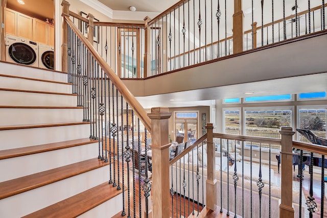 stairs with crown molding, a towering ceiling, and washer and dryer