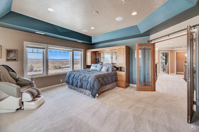 4428 Fox View Loop, Helena, MT 59602 - bedroom with light carpet, a barn door, a textured ceiling, recessed lighting, and a raised ceiling