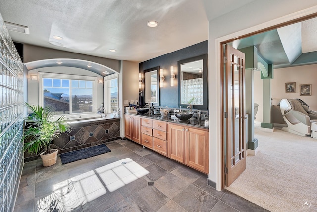 bathroom featuring a relaxing tiled tub, vanity, and a textured ceiling