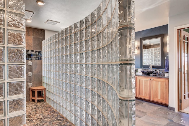 bathroom with vanity, a textured ceiling, and a tile shower