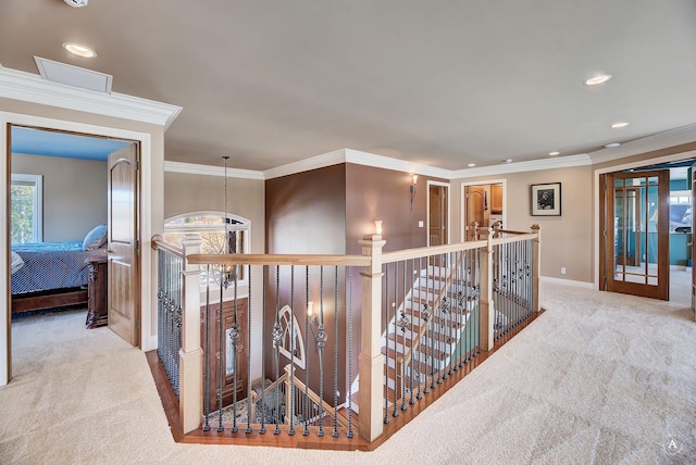 hall featuring light carpet, crown molding, and a chandelier