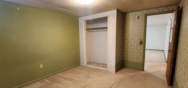 unfurnished bedroom featuring light colored carpet and a closet