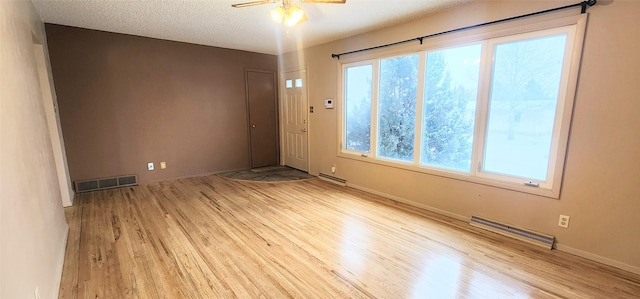 empty room with ceiling fan, light hardwood / wood-style flooring, and a textured ceiling