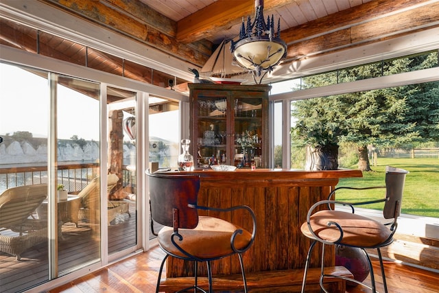 bar featuring plenty of natural light, beam ceiling, and light hardwood / wood-style flooring