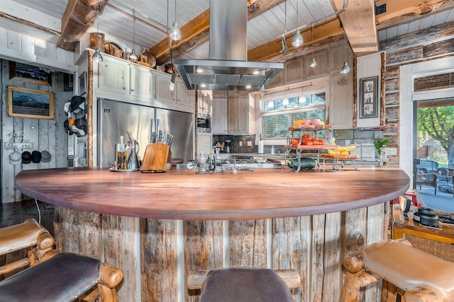 kitchen with built in fridge, plenty of natural light, island range hood, and beam ceiling