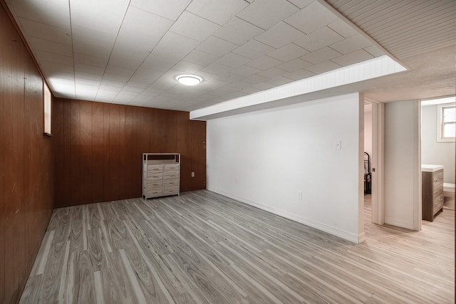 basement with wooden walls and light wood-type flooring