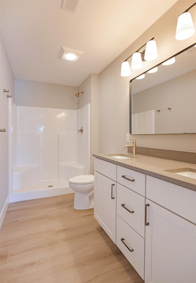 bathroom featuring hardwood / wood-style flooring, vanity, toilet, and walk in shower