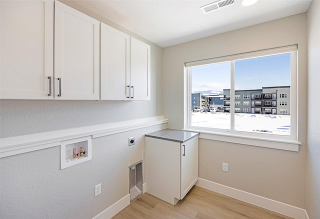 clothes washing area featuring cabinets, hookup for an electric dryer, hookup for a washing machine, and light hardwood / wood-style flooring