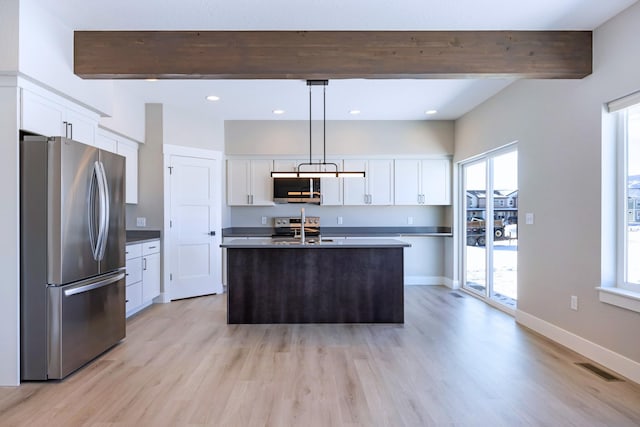 kitchen featuring appliances with stainless steel finishes, decorative light fixtures, a center island with sink, and white cabinets