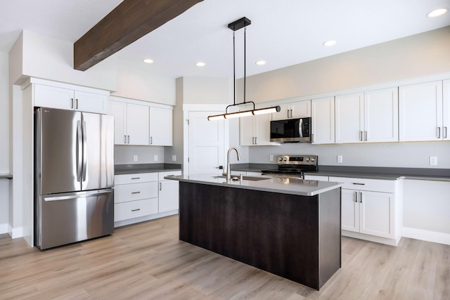 kitchen with sink, appliances with stainless steel finishes, white cabinetry, a center island with sink, and decorative light fixtures