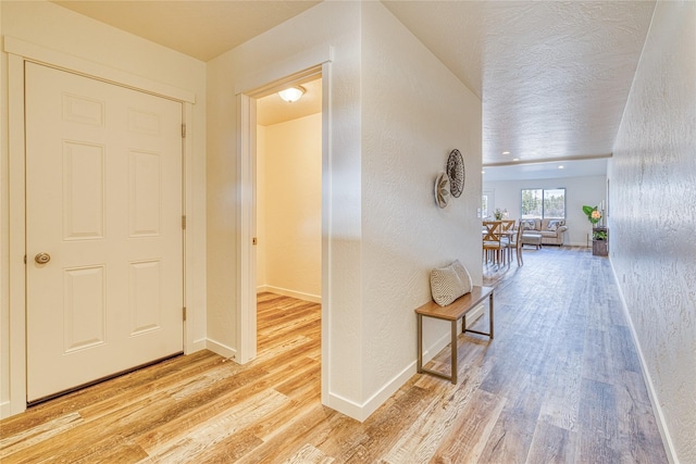 corridor featuring light hardwood / wood-style flooring and a textured ceiling