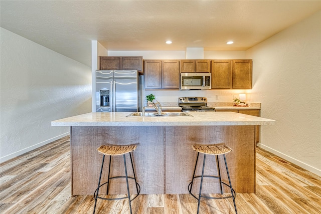 kitchen with sink, stainless steel appliances, and a center island with sink