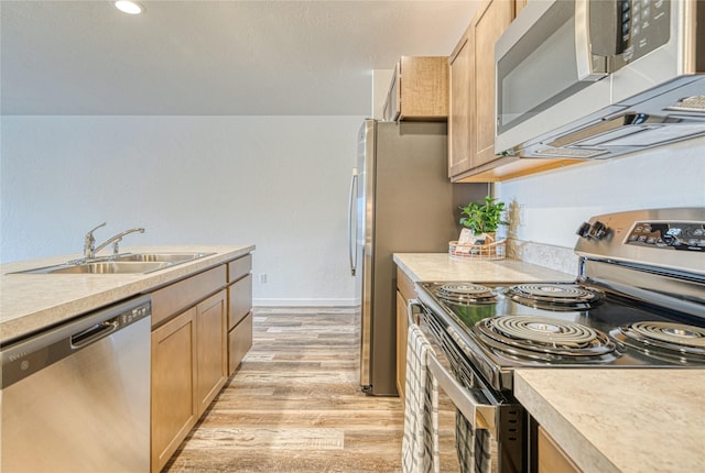 kitchen featuring appliances with stainless steel finishes, light brown cabinetry, sink, and light wood-type flooring