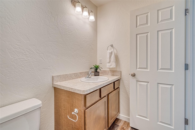 bathroom featuring wood-type flooring, vanity, and toilet