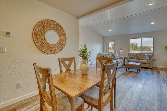 dining space with lofted ceiling and light hardwood / wood-style flooring