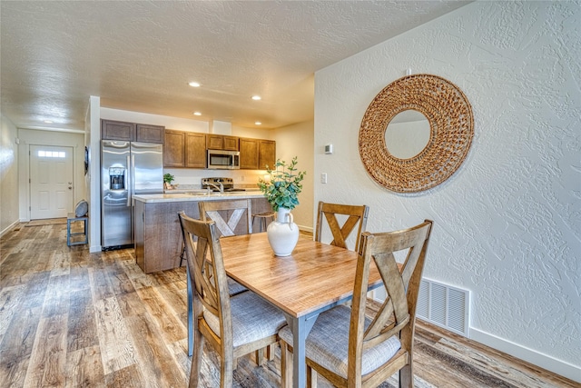 dining space with hardwood / wood-style flooring, sink, and a textured ceiling