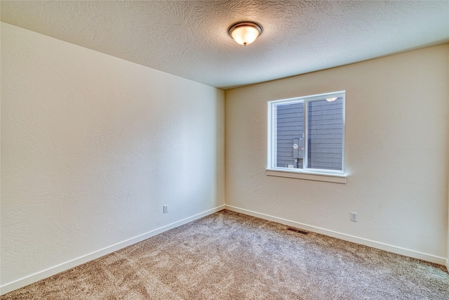 spare room featuring carpet floors and a textured ceiling